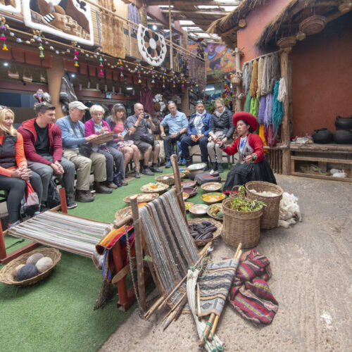 Woman dressed in local clothes showing tourists how to make a scarf made of Alpaca wool in the city of Chinchero, Peru.