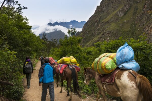 Sacred Valley, Peru - January 1, 2014: People and horses carrying goods along the Inca Trail, in the Sacred Valley, Peru