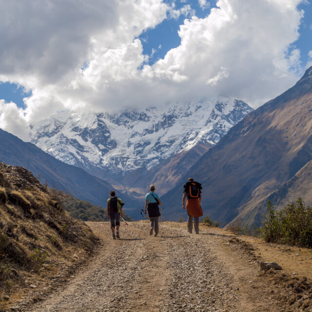 "Cusco, Peru - August 25, 2009: There travellers can be seen walking along a mountain road with a large mountain peak in the background partly shrouded in cloud. The road leads towards the Salcantay glacier in the Peruvian Andes near Machu Picchu and the path is a popular budget alternative to trekking the Inca trail."