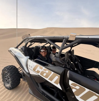 Two travellers smiling in a dune buggy in the Huacachina desert, Peru
