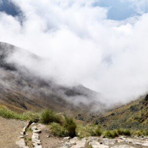 Hispanic man at the mountain pass known as Dead Woman's Pass, on the historical Inca trail, which goes through the mountains to Machu Picchu. Man at over 4000 m high altitude, seeing the clouds coming in covering the mountains. Photo taken on the Inca trail, Peru on November 3, 2018